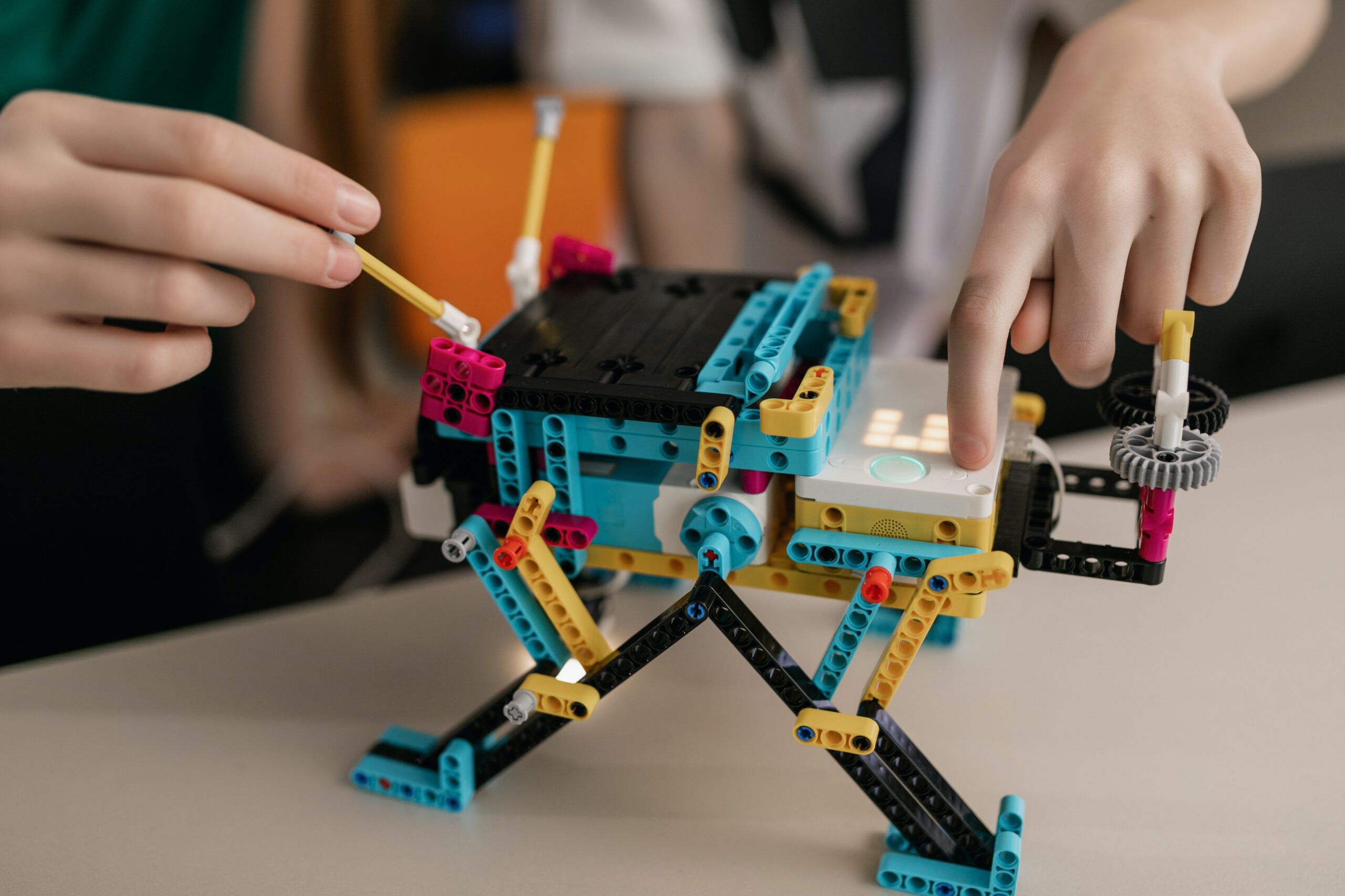 Chłopczyk układający robota z kolorowych klocków LEGO na stole