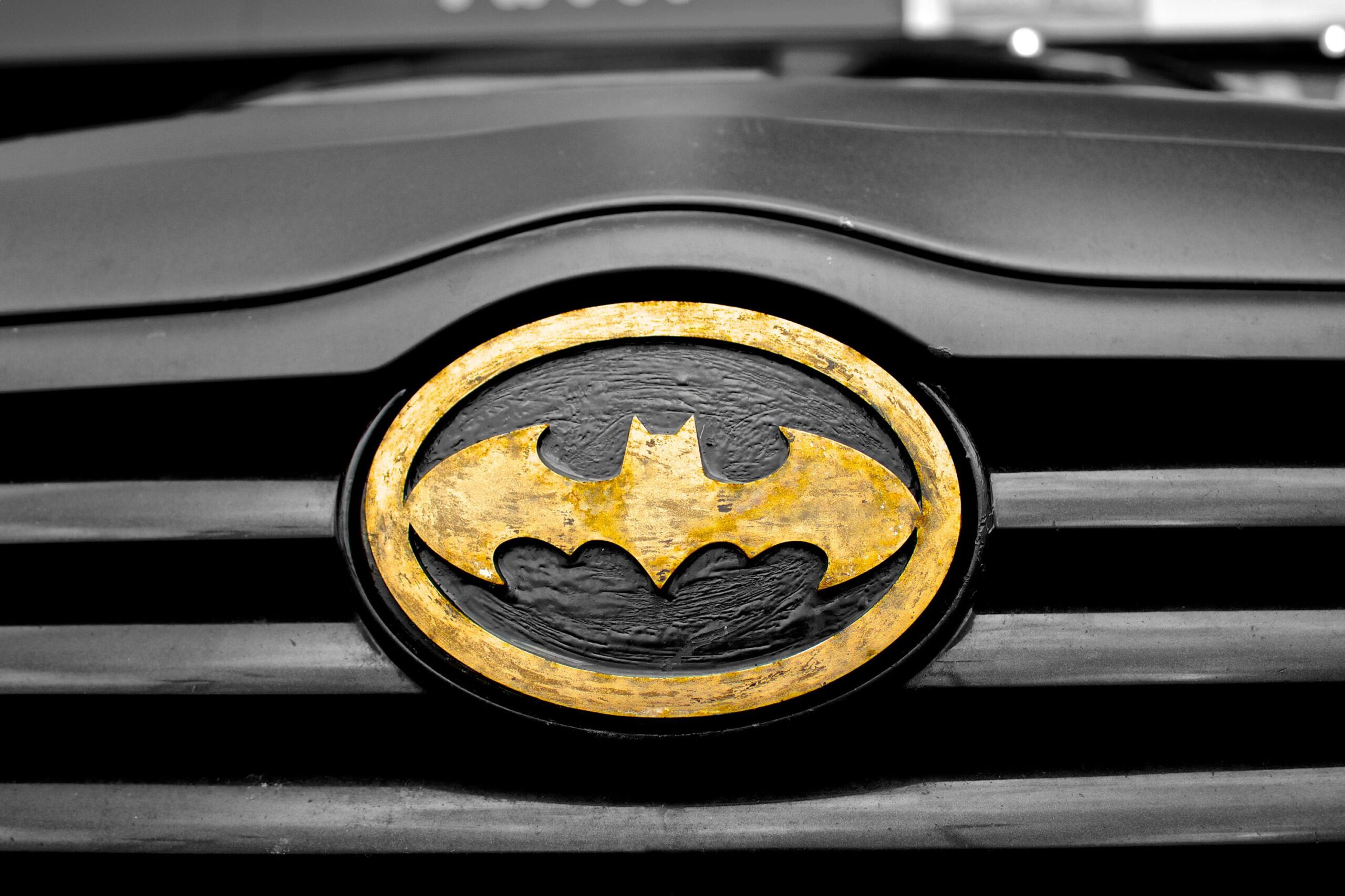 Logo Batmana z żółtym elementem na czarnej masce samochodu