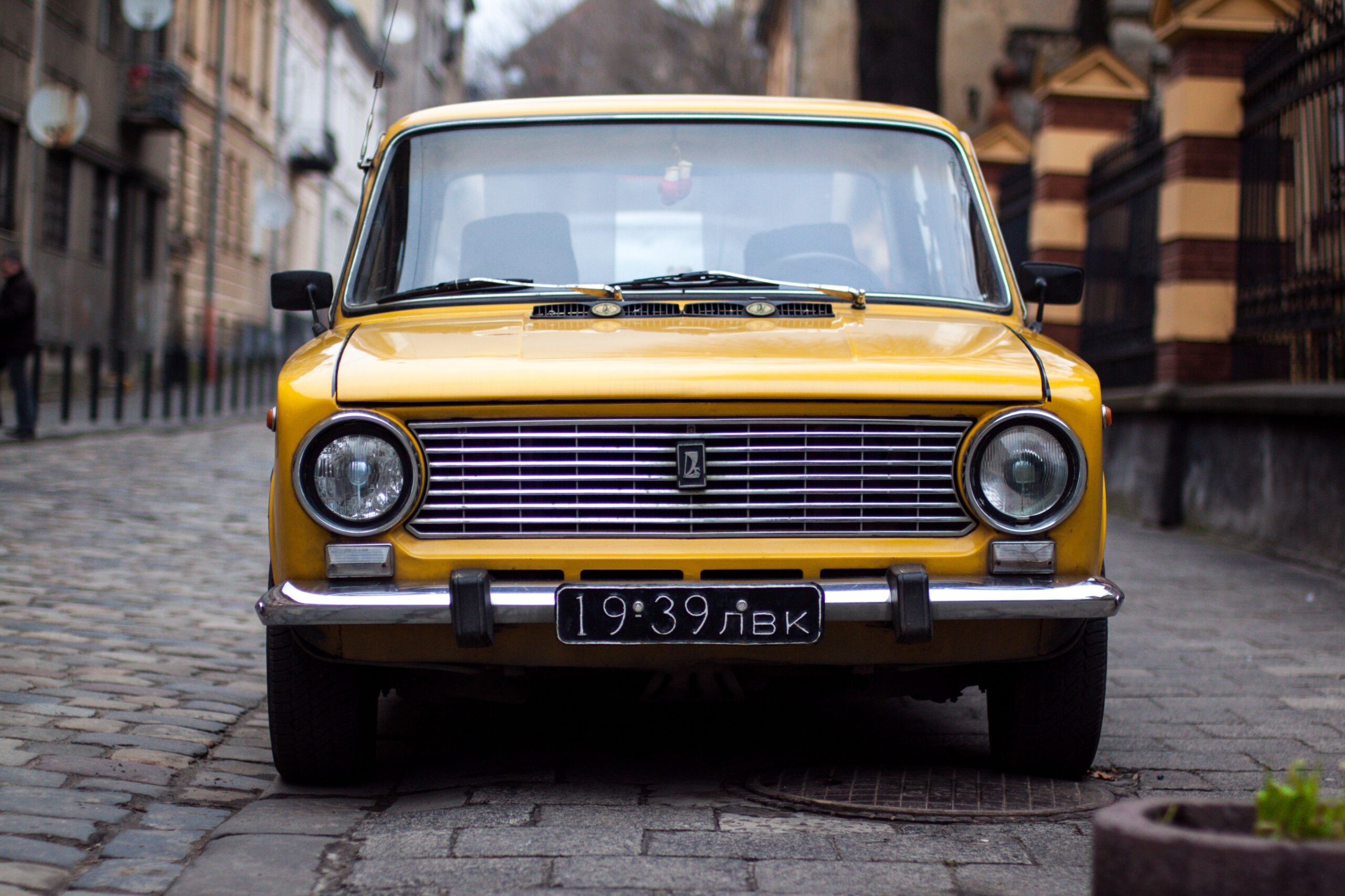 Stary żółty samochód stojący na wąskiej brukowanej uliczce